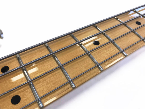 Close-up of electric bass guitar maple fretboard with metal frets and round black position markers on white background