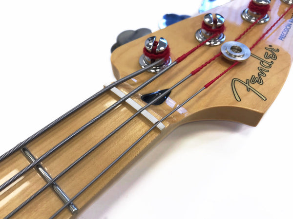 Close-up of Fender Precision Bass guitar headstock with chrome tuning pegs and steel strings against white background