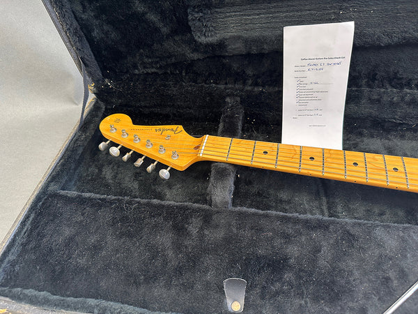 Fender Stratocaster guitar neck and headstock inside black plush guitar case with Coffee House Guitars pre sales checklist in the background