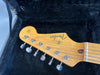 Fender Stratocaster guitar headstock with tuning pegs and strings in black padded guitar case