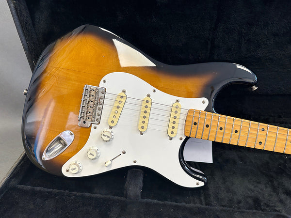 Sunburst electric guitar with maple fretboard, three single-coil pickups, white pickguard, volume and tone knobs, inside black guitar case