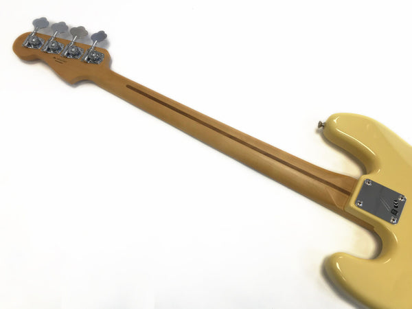 Back view of electric bass guitar neck with maple wood and four chrome tuning pegs, cream-colored body with metal neck plate, isolated on white background