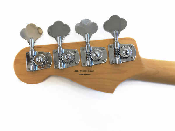 Close-up of natural wood bass guitar headstock with four chrome tuning pegs and serial number MX18121667 made in Mexico on white background