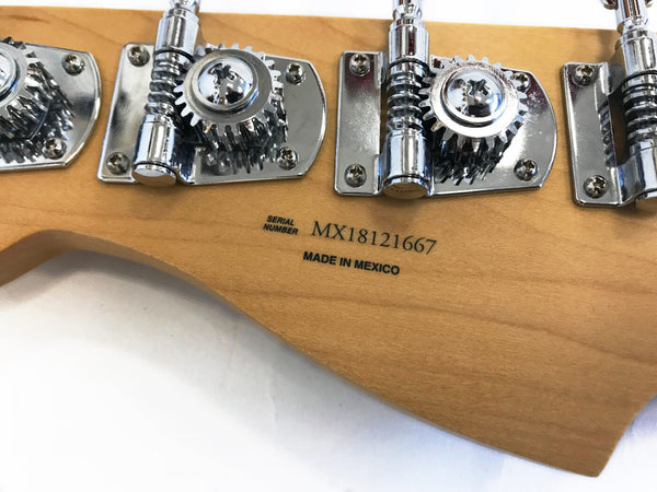 Close-up of guitar headstock back showing chrome tuning pegs and serial number MX18121667 with "Made in Mexico" marking on natural wood finish