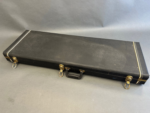 Black rectangular hard guitar case with metal latches and a handle on gray background