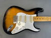 Close-up of sunburst electric guitar body with white pickguard and maple neck on gray background at Coffee House Guitars