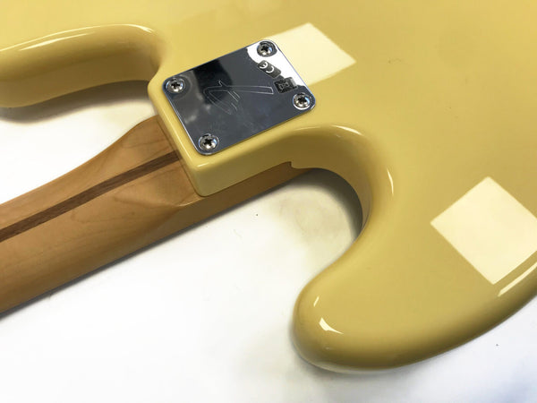 Close-up of beige electric guitar back with maple neck and metal neck plate featuring four screws and etched logo