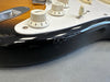 Close-up of electric guitar body showing cream tone control knobs and black finish with scratch damage near edge, from Coffee House Guitars product listing.