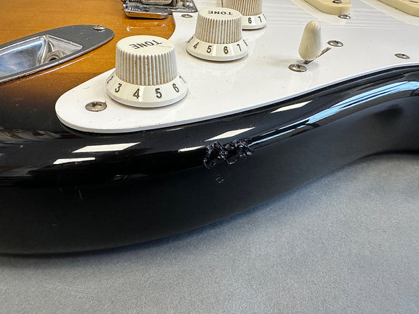 Close-up of electric guitar body showing cream tone control knobs and black finish with scratch damage near edge, from Coffee House Guitars product listing.