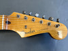 Close-up of Fender Stratocaster guitar headstock with six tuning pegs and natural wood finish on Gray background
