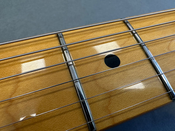 Close-up of maple guitar fretboard with metal frets and black dot inlay, steel guitar strings on Coffee House Guitars acoustic guitar neck