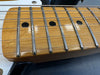 Close-up of maple guitar neck with metal frets and black dot inlays on electric guitar fretboard