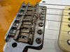 Close-up of vintage Fender guitar bridge and saddle with six strings and metal screws on a sunburst electric guitar body