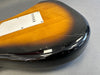Close-up of sunburst electric guitar body back with white plastic cover and visible surface scratches and cracks