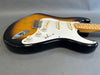 Sunburst electric guitar body with white pickguard, three single-coil pickups, and maple neck on gray background