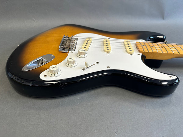 Sunburst electric guitar body with white pickguard, three single-coil pickups, and maple neck on gray background