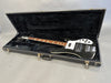 Black electric bass guitar with white pickguard and multiple control knobs in open black hard case with plush interior at Coffee House Guitars