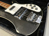 Close-up of black electric bass guitar with chrome bridge and control knobs in black plush case