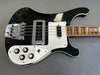 Black and white electric bass guitar with chrome bridge, four control knobs, toggle switch, and rosewood fretboard on grey background