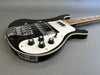 Black and white electric bass guitar with chrome hardware and four control knobs on grey background
