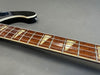 Close-up of electric guitar neck showing rosewood fingerboard with triangular inlays and metal frets on gray background
