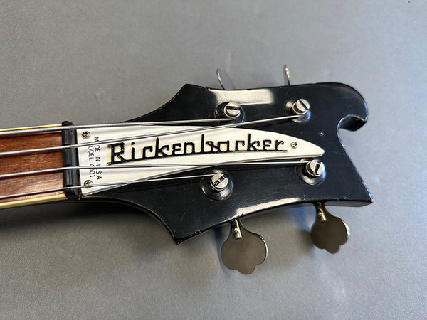Close-up of vintage Rickenbacker Model 4010 bass guitar black headstock with tuning pegs and silver logo plate
