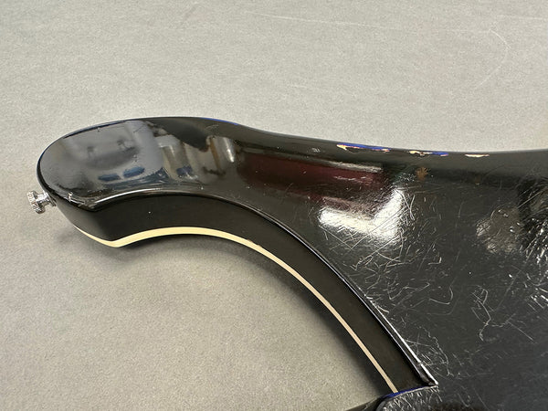 Close-up of the black guitar body with cream binding showing scratches and wear on the finish near the neck joint.