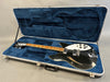 Black semi-hollow body electric guitar with white pickguard and maple fretboard in blue plush-lined hard case on gray background