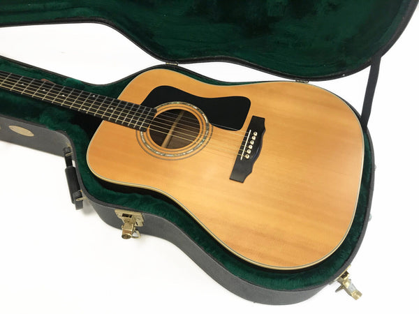 Acoustic dreadnought guitar with natural wood finish inside green velvet lined hard case