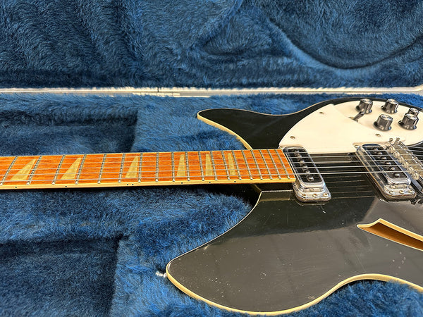 Black electric guitar with cream pickguard and maple fretboard in blue plush guitar case, close up of neck and body