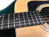 Close-up view of acoustic guitar fretboard and soundhole with steel strings and dot inlays, natural wood finish and black pickguard