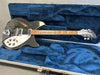 Vintage black Rickenbacker electric guitar with white pickguard and trapezoid inlays resting in blue plush lined hard case
