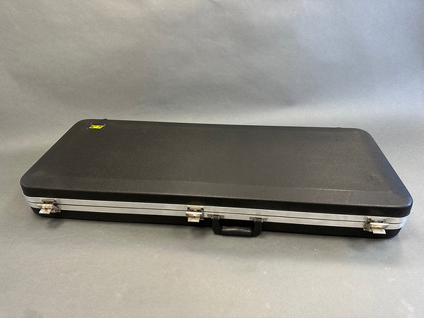 Black rectangular hard guitar case with metal latches and handle on gray background