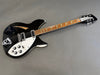Black Rickenbacker electric guitar with white pickguard and chrome hardware on gray background