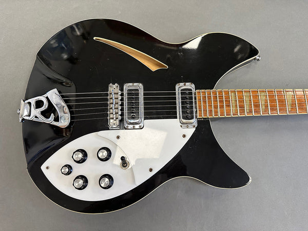 Black semi-hollow body electric guitar with white pickguard, two pickups, five control knobs, toggle switch, and a rosewood fretboard on gray background