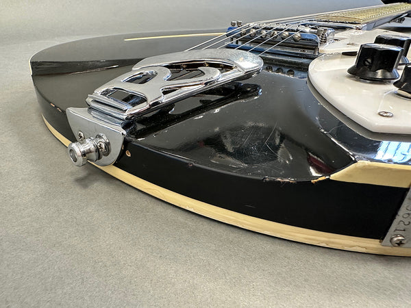 Close-up of black vintage electric guitar body showing chrome trapeze tailpiece, white pickguard, control knobs, and worn edges on Coffee House Guitars product listing