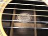 Close-up of Guild acoustic guitar interior label showing model DV52-NT S and serial number ADS22614 made in USA with visible wooden bracing and guitar strings in foreground