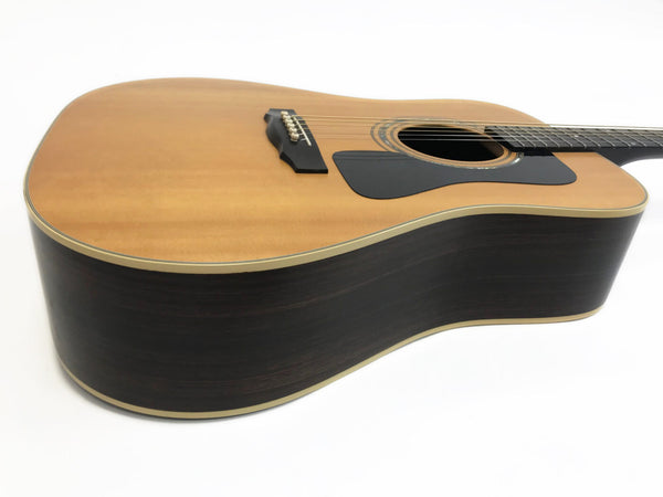Acoustic guitar with natural wood top and dark wood sides displayed on white background from angled side view