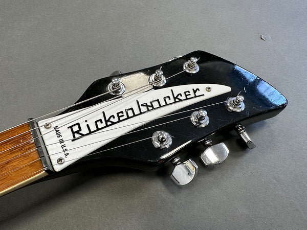Close-up of black Rickenbacker guitar headstock with vintage tuning pegs and white logo plate showing "Made in U.S.A." text