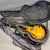 Semi-hollow electric guitar with sunburst finish inside black hard shell case lined with gray plush interior, guitar cover partially unfolded on gray surface