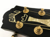 Close-up of black Guild guitar headstock with gold tuning pegs and mother-of-pearl inlay logo and crown design