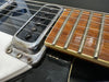 Close-up of electric guitar pickup, strings, and fretboard showing metal frets and wood grain on fretboard at Coffee House Guitars