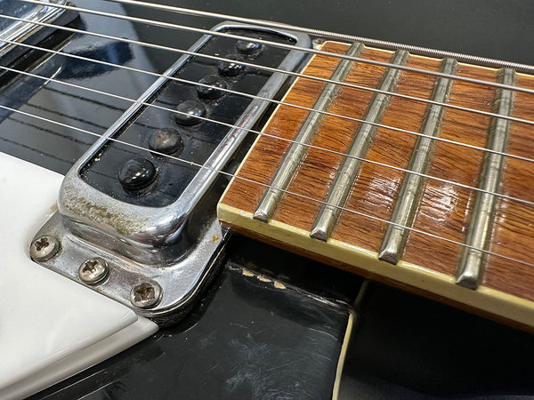 Close-up of electric guitar pickup, strings, and fretboard showing metal frets and wood grain on fretboard at Coffee House Guitars