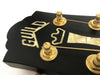 Close-up of Guild guitar headstock featuring mother-of-pearl inlay logo and vintage gold tuning pegs