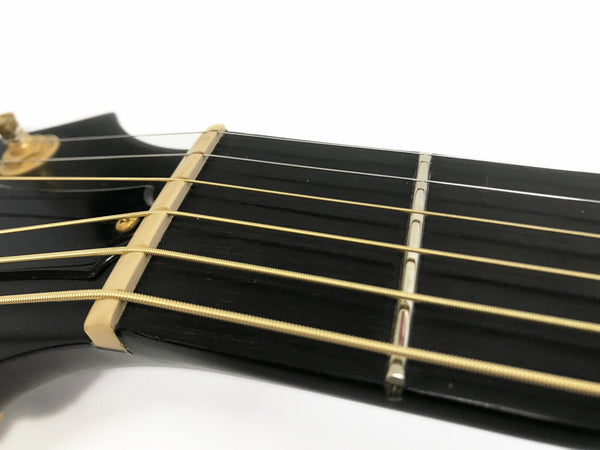 Close-up of guitar headstock and nut with gold tuning peg and strings on black fretboard