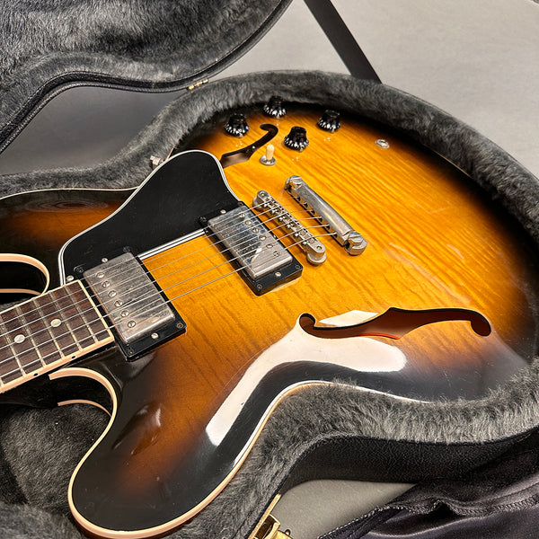 Semi-hollow body electric guitar with sunburst finish and dual humbucker pickups in protective guitar case with plush lining