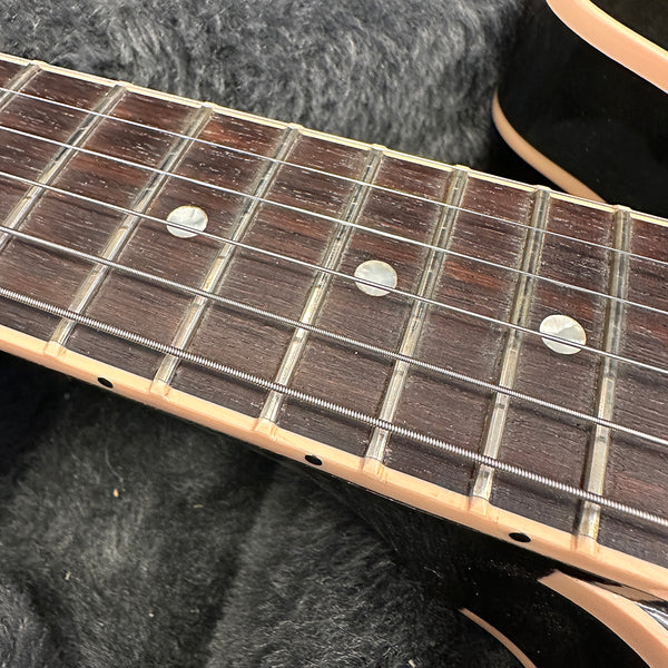 Close-up of rosewood guitar fretboard with metal frets, mother-of-pearl dot inlays, and steel strings on black electric guitar body
