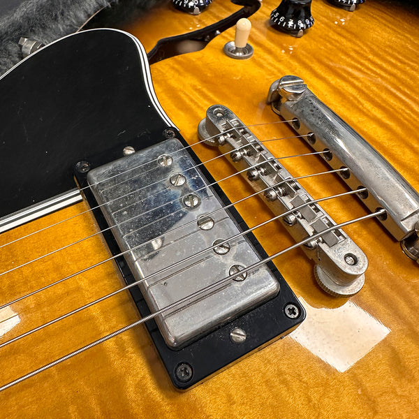 Close-up of electric guitar bridge, chrome pickup, and strings on honey burst finish body at Coffee House Guitars