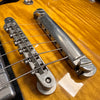 Close-up of vintage electric guitar bridge and tailpiece on sunburst finish body showing metal saddles and strings