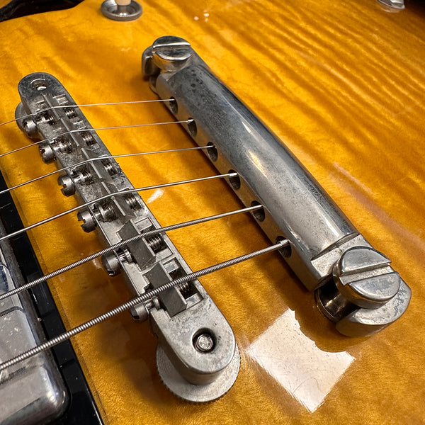 Close-up of vintage electric guitar bridge and tailpiece on sunburst finish body showing metal saddles and strings